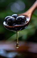 Fresh black cherries on wooden spoon with honey dripping, macro shot against dark green background, dramatic lighting highlights glossy fruit surface.