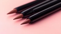 Black wooden pencils and pen arranged diagonally on pink background with soft focus and minimalist composition for stationery and office supplies concept.
