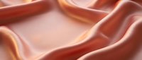 Luxurious coral pink silk fabric with elegant flowing waves and soft golden highlights creating smooth textile drape for fashion and interior design projects.
