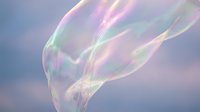 Iridescent soap bubble with rainbow reflections floating against soft pastel gradient background creating dreamy ethereal atmosphere for wellness concepts.