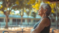Senior Caucasian woman in athletic wear enjoying peaceful moment outdoors during sunset, eyes closed with serene expression against golden bokeh background.