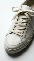 White leather sneaker with flat laces on a light background, showcasing minimalist style and clean design for fashion and footwear concepts.