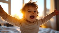 Happy toddler with arms outstretched laughing joyfully at sunrise, wearing cream sweater. Natural window lighting creates warm golden glow, capturing pure childhood joy.