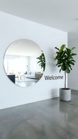 Modern minimalist entryway with large round mirror, welcome sign, and fiddle leaf fig plant on polished concrete floor in bright white interior.