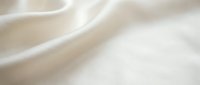 Soft cream colored fabric with gentle flowing waves and smooth texture creating elegant drapery folds for luxury textile and fashion design backgrounds.