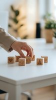 Hand arranging wooden blocks with wellness symbols including heart, brain, lotus and meditation icons on white table for mindfulness and mental health concepts.
