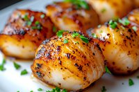 Pan seared sea scallops with caramelized crust garnished with fresh herbs on white plate, extreme close up macro food photography with selective focus.