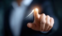 Business professional touching glowing growth chart arrow pointing upward on dark background, representing financial success and market performance.