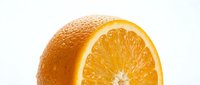 Whole orange fruit with fresh cut slice showing juicy citrus segments and vibrant yellow flesh against white background for food and beverage design.
