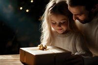 Young girl with blonde hair and father in white sweater looking at glowing gift box with magical expression during holiday celebration, warm bokeh lights.