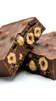 Broken dark chocolate pieces with roasted hazelnuts embedded inside, isolated on white background for confectionery, food packaging, and culinary design projects.