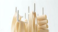 Assorted uncooked pasta shapes including penne, rigatoni, and spaghetti arranged upright on white background for cooking, food preparation, and culinary design projects.