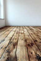 Empty room interior with rustic wooden floorboards, white walls and window, showing natural aged pine planks with distinctive grain patterns and knots.
