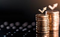 Stacked coins with upward arrow and heart symbols on dark background showing financial growth, investment success and wealth accumulation concept.