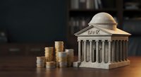 Miniature bank building with classical columns and stacks of golden coins on wooden desk representing financial services, savings, investment concepts.