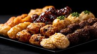 Assorted Japanese yakitori skewers with chicken, pork and beef glazed in sweet soy sauce, arranged on black plate against dark background. Authentic Asian cuisine.