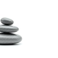 Stack of three smooth gray zen stones balanced on white background for spa wellness meditation and mindfulness concepts.