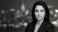 Professional businesswoman with dark hair in corporate attire against blurred city lights background for business and career concepts.