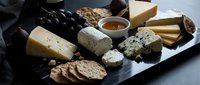 Gourmet cheese board with artisanal varieties, crackers, grapes and honey for wine tasting, restaurant menus and culinary presentations.