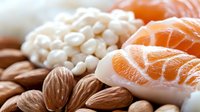 Fresh salmon sashimi slices with raw almonds and white beans on wooden surface, macro food photography for restaurant menu and culinary design.