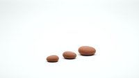 Three smooth brown oval stones arranged in ascending size order on white background for zen meditation spa wellness design concepts.