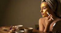 Young woman applying facial serum in spa setting with towel wrapped hair enjoying skincare routine and wellness treatment for healthy glowing skin.