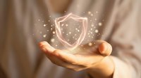 Businessman holding glowing shield icon with particles, representing cybersecurity, data protection, and digital safety for business and technology concepts.