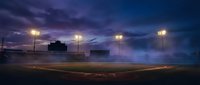 Empty baseball field at twilight with stadium lights illuminated against dramatic purple sky, perfect for sports and recreation themes.