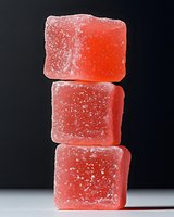 Red fruit gummy candies stacked on dark background, isolated confectionery sweets coated with sugar crystals for packaging design and food advertising.