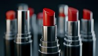 Red lipsticks arranged in row with selective focus on center lipstick, showing metallic silver tubes against dark background, makeup and cosmetics concept.
