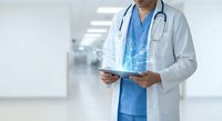 Male doctor in white coat holding digital tablet with holographic medical interface display in modern hospital corridor for healthcare technology concepts.