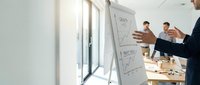 Business team analyzing data charts on whiteboard during corporate strategy meeting in modern office conference room.