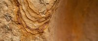 Layered sandstone rock formation with natural striations and warm earth tones showcasing geological sedimentary patterns and textures for educational content.