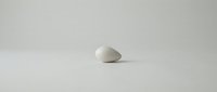 Single white smooth stone or pebble isolated on neutral background, suitable for minimalist design, wellness concepts, zen meditation themes, and spa-related projects.