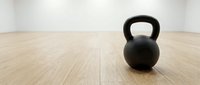 Black kettlebell weight on wooden gym floor, fitness training equipment for strength and conditioning workouts.