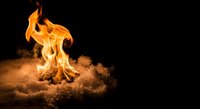 Campfire flames burning brightly in sandy ground against dark background, outdoor adventure and wilderness survival concept for camping designs.