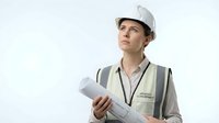 Male construction worker, Caucasian ethnicity, wearing white hard hat and safety vest, holding rolled blueprints while looking upward thoughtfully against white background. Suitable for construction, engineering, architecture, and industrial business projects.