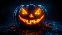 Glowing neon jack o'lantern with orange light emanating from carved face sits on dark surface surrounded by scattered autumn leaves, creating spooky Halloween atmosphere.