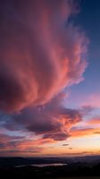 Dramatic sunset sky with vibrant pink and purple clouds over landscape with lake view for nature photography and atmospheric backgrounds.