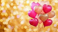 Heart-shaped pink and gold balloons floating against golden bokeh background with soft glowing lights, romantic festive celebration atmosphere.