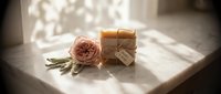 Handmade soap bars with natural ingredients and dried rose flower on marble surface in sunlight, suitable for spa, wellness, and beauty product marketing.