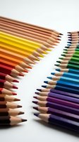 Sharpened colored pencils arranged in gradient rows from warm yellows and reds to cool blues and purples on white background for art and design projects.