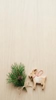 Wooden reindeer ornament with evergreen branch and pinecone on light wood surface, ideal for holiday decorations and seasonal design projects.