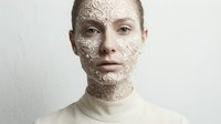 Young Caucasian woman with intricate ornamental patterns covering face and neck in neutral tones for beauty and skincare concepts.
