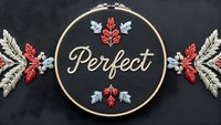 Embroidery hoop with Perfect text and autumn leaves on dark background. Handmade needlework craft for seasonal home decor and textile art projects.
