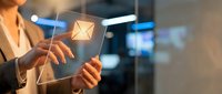 Businesswoman holding glowing email icon with digital interface, representing online communication, networking, and modern business technology solutions.
