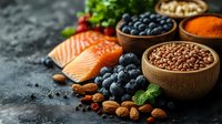Raw salmon fillets with fresh blueberries, almonds, flax seeds and spices on dark background. Healthy omega-3 rich superfoods and antioxidant ingredients.