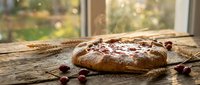 Homemade cranberry bread loaf with fresh berries on rustic wooden table by sunny window. Artisan baking, cozy kitchen atmosphere for food blogs and recipes.