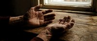 Elderly hands reaching upward on wooden floor near window, expressing hope, prayer, or desperation in dramatic lighting for emotional storytelling concepts.