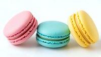 Colorful French macarons in pink, turquoise and yellow on white background. Sweet pastry dessert cookies isolated for bakery menu design and culinary projects.